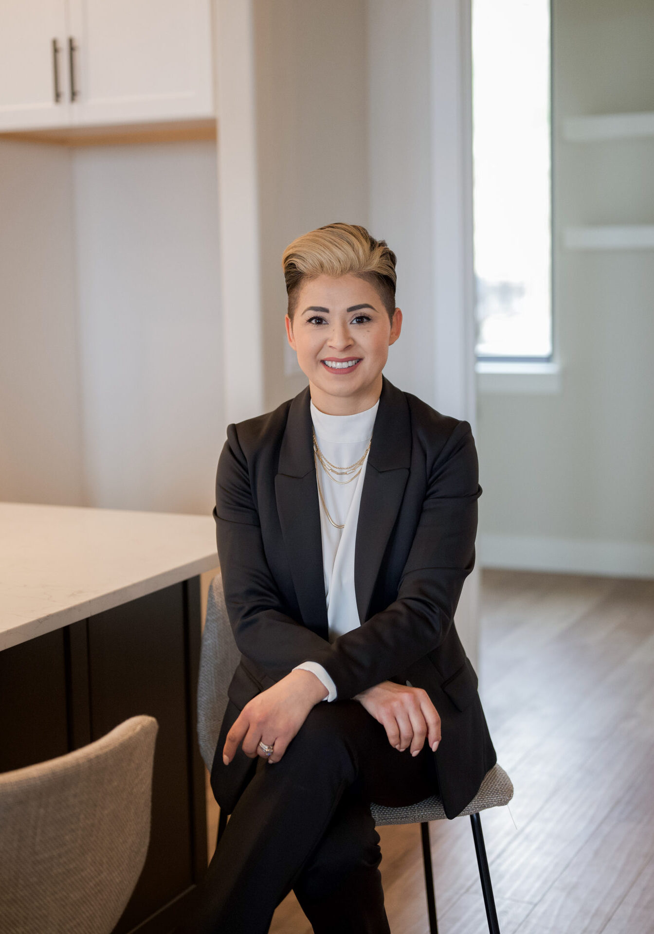 Professional woman in business attire sitting and smiling in office.
